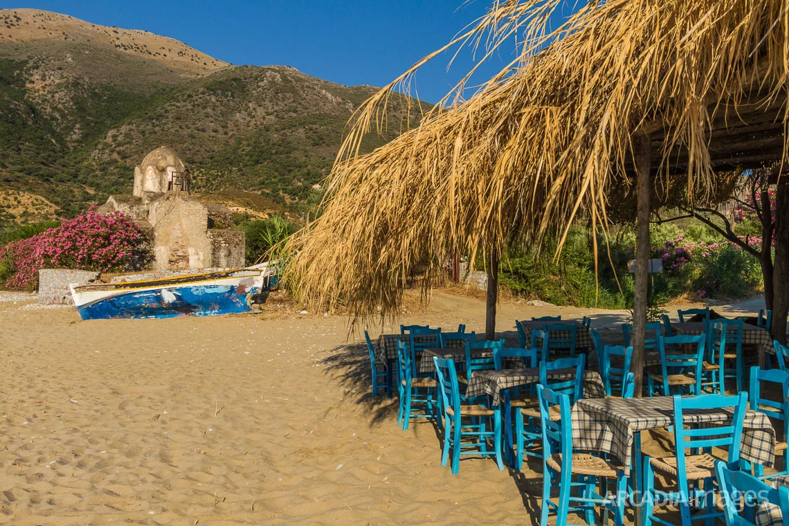 The chairs of a beach fish-tavern and the Byzantine church of Aghia Varvara in the background. Skoutari, Laconia, Peloponnese
