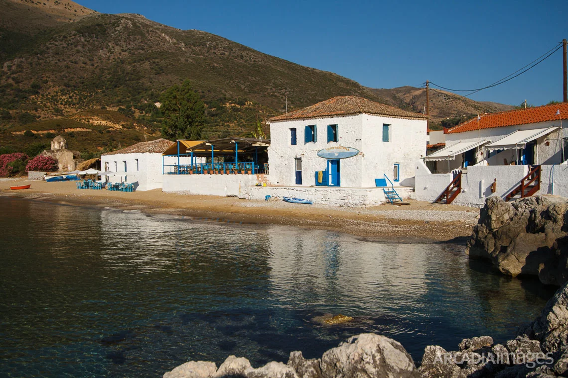 Aghia Varvara beach, a fish-tavern and the Byzantine church of Agia Varvara in the background. Skoutari, Laconia, Peloponnese